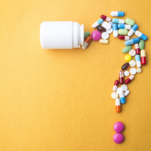 Pills or capsules as a question mark and white plastic bottle.